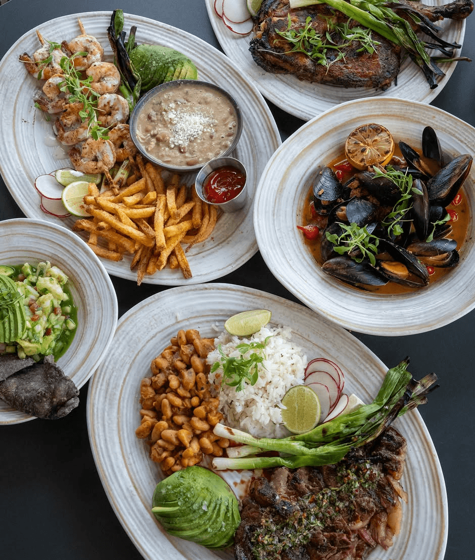 A spread of High Marea plates with grilled shrimp, steak, mussels, rice, beans and avocado