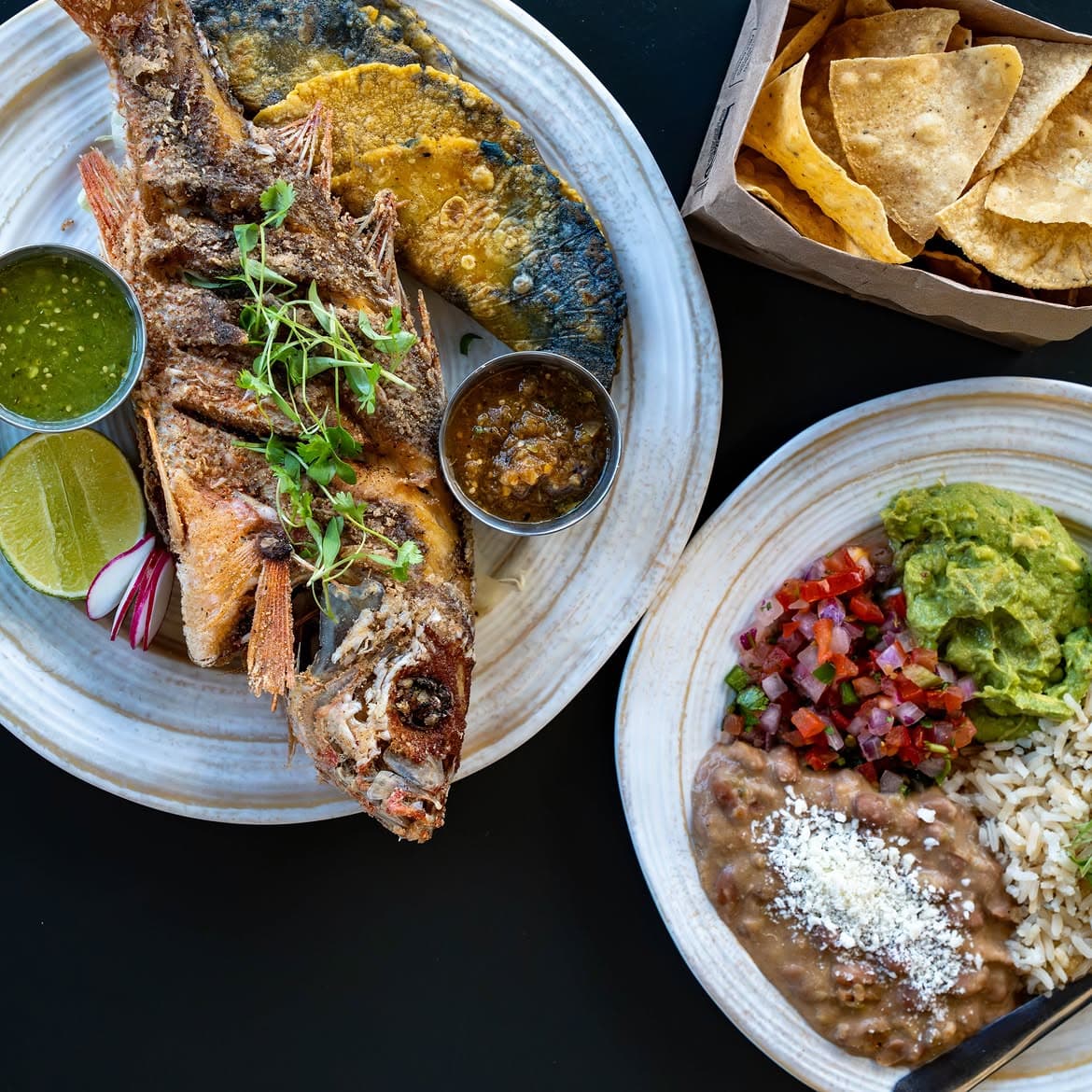 High Marea whole fish plate with rice, beans, guacamole and tortilla chips.